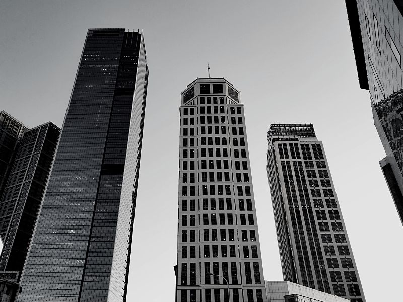 Looking up at several skyscrapers from street level.