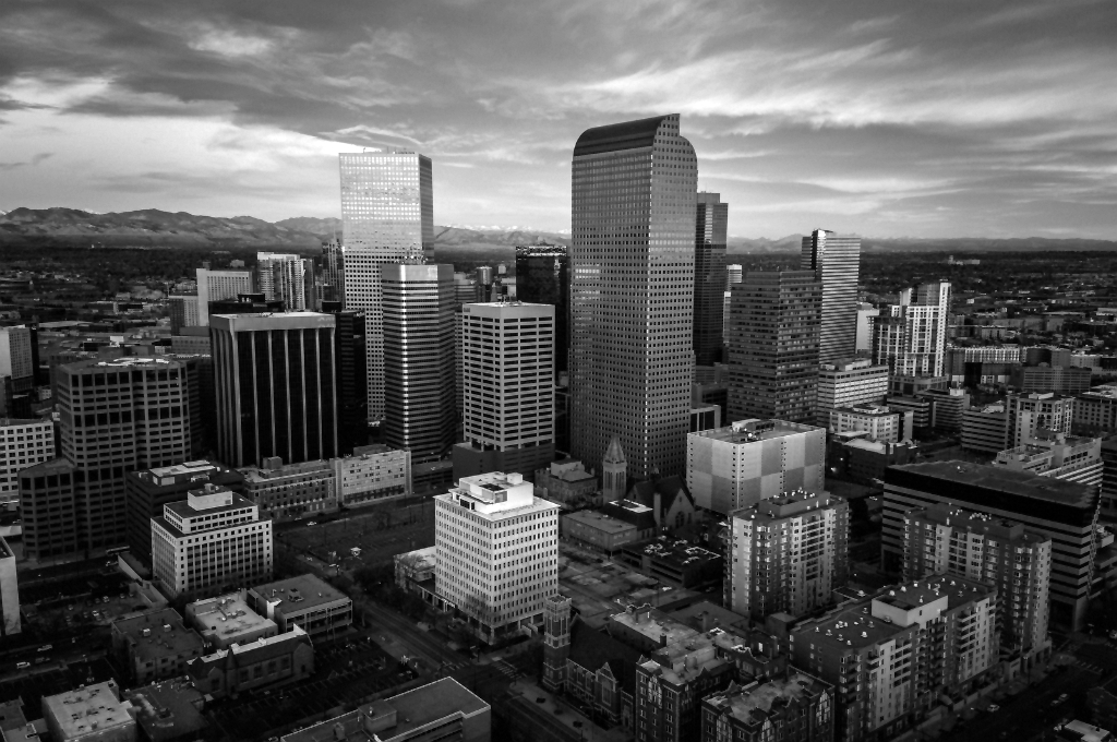 The city skyline of Denver, CO at dusk. The photo is in grayscale showing the skyscrapers of the city behind it. Reveille Advisors works from Denver to serve our Colorado market.