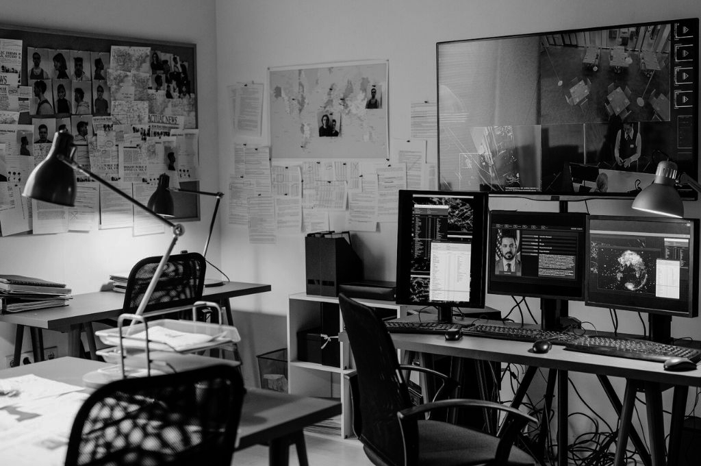 Private intelligence operatives or investigators commonly use a variety of tools to perform their investigations. In this photo we see an office filled with several computers and files, implying this is the investigator's workspace.