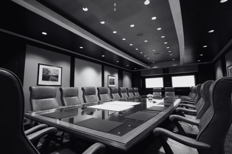 A photo of an executive boardroom with a long wooden table surrounded by leather chairs. Reveille Advisors provides HR consulting services.